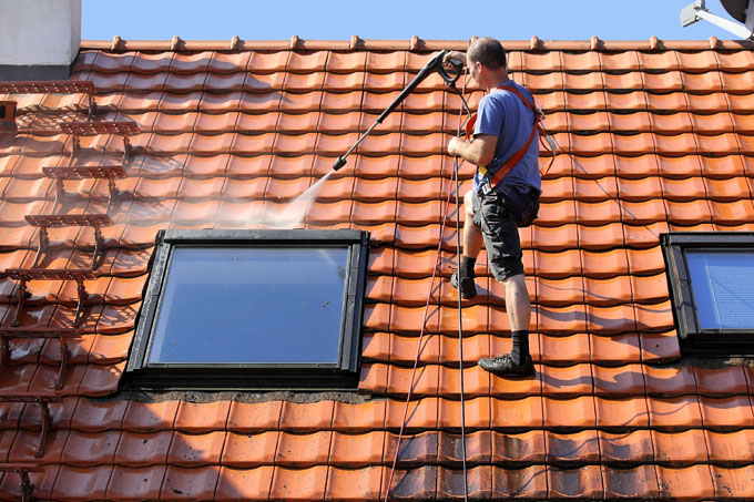 Team member jet cleans roof around sky light