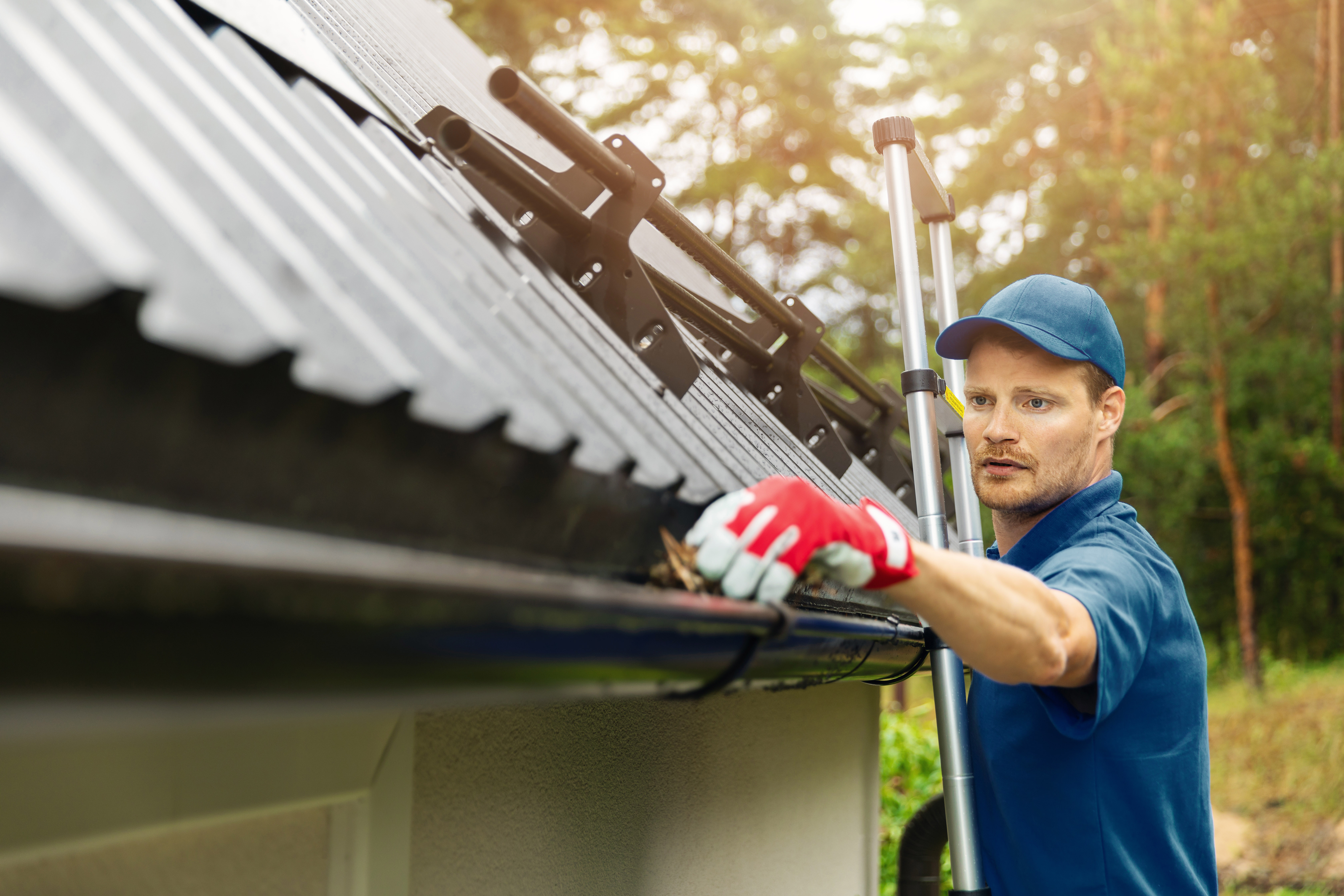 Team member clears gutter of blockage from leaves and dirt.